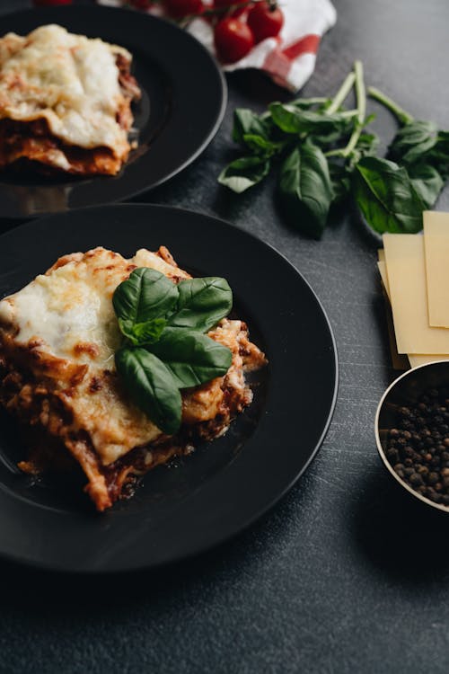 Free Lasagna on Black Plate With Basil Leaves On Top Stock Photo