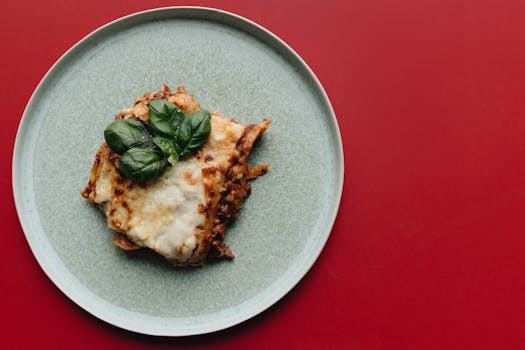 Delicious Italian lasagna topped with fresh basil served on a minimalist plate.