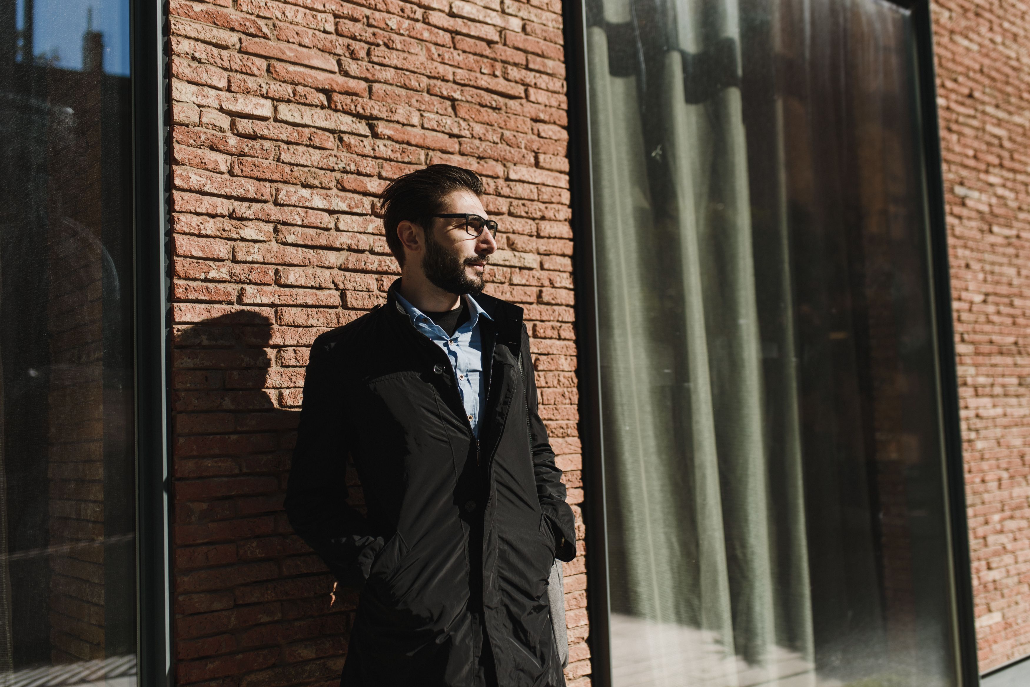 A Man Standing while Leaning on a Brick Wall · Free Stock Photo