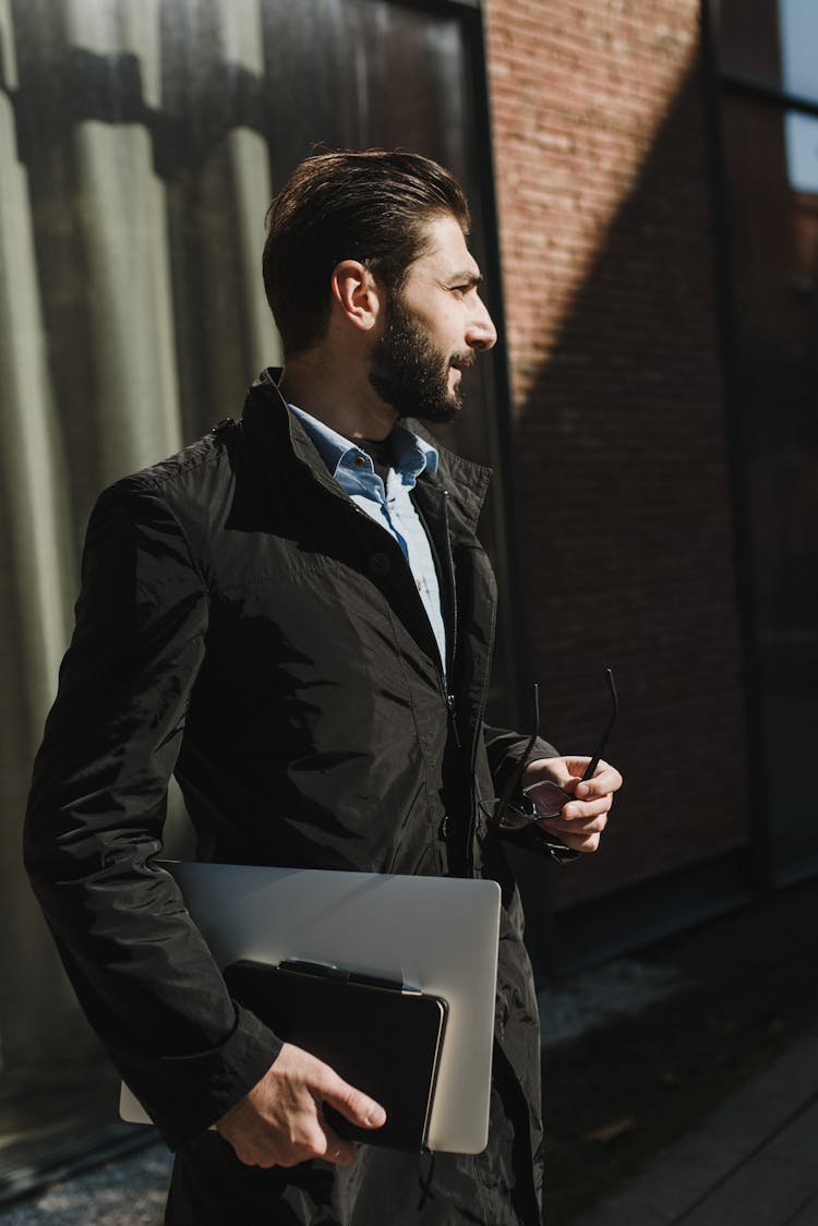 Man In Black Jacket Carrying A Laptop