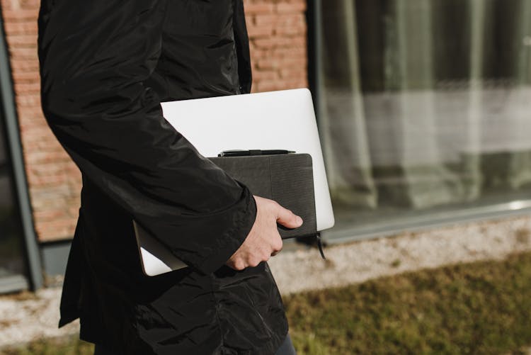 Person Carrying A Laptop And A Book