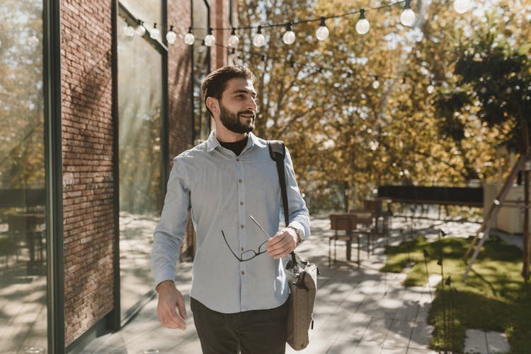 Man Wearing Long Sleeves Polo Walking Beside A Building