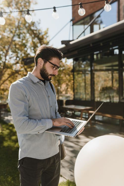 Man Using a Laptop While Standing · Free Stock Photo