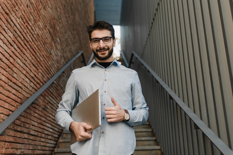 A Handsome Smiling Man Carrying A Laptop