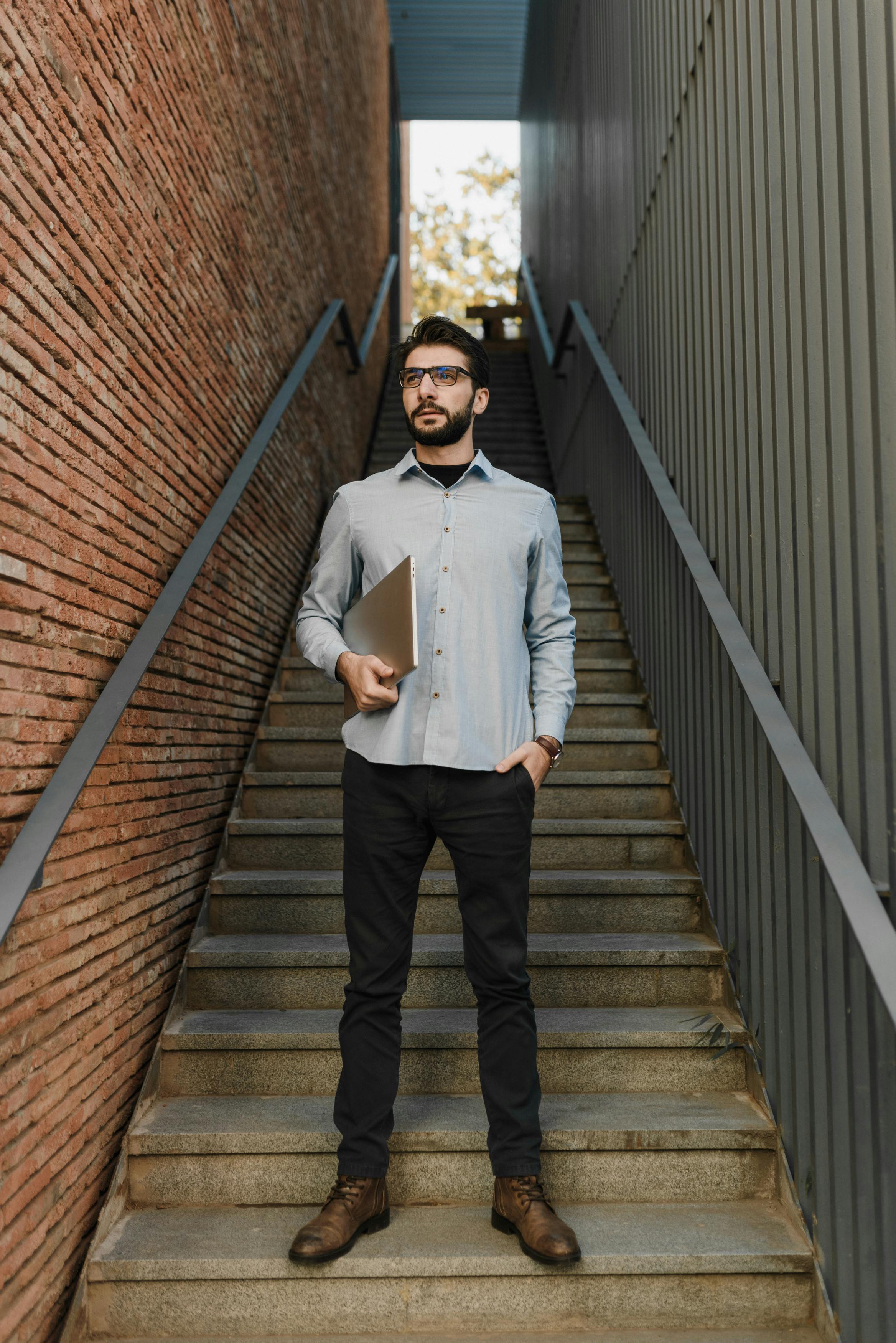 man standing on the staircase holding a laptop