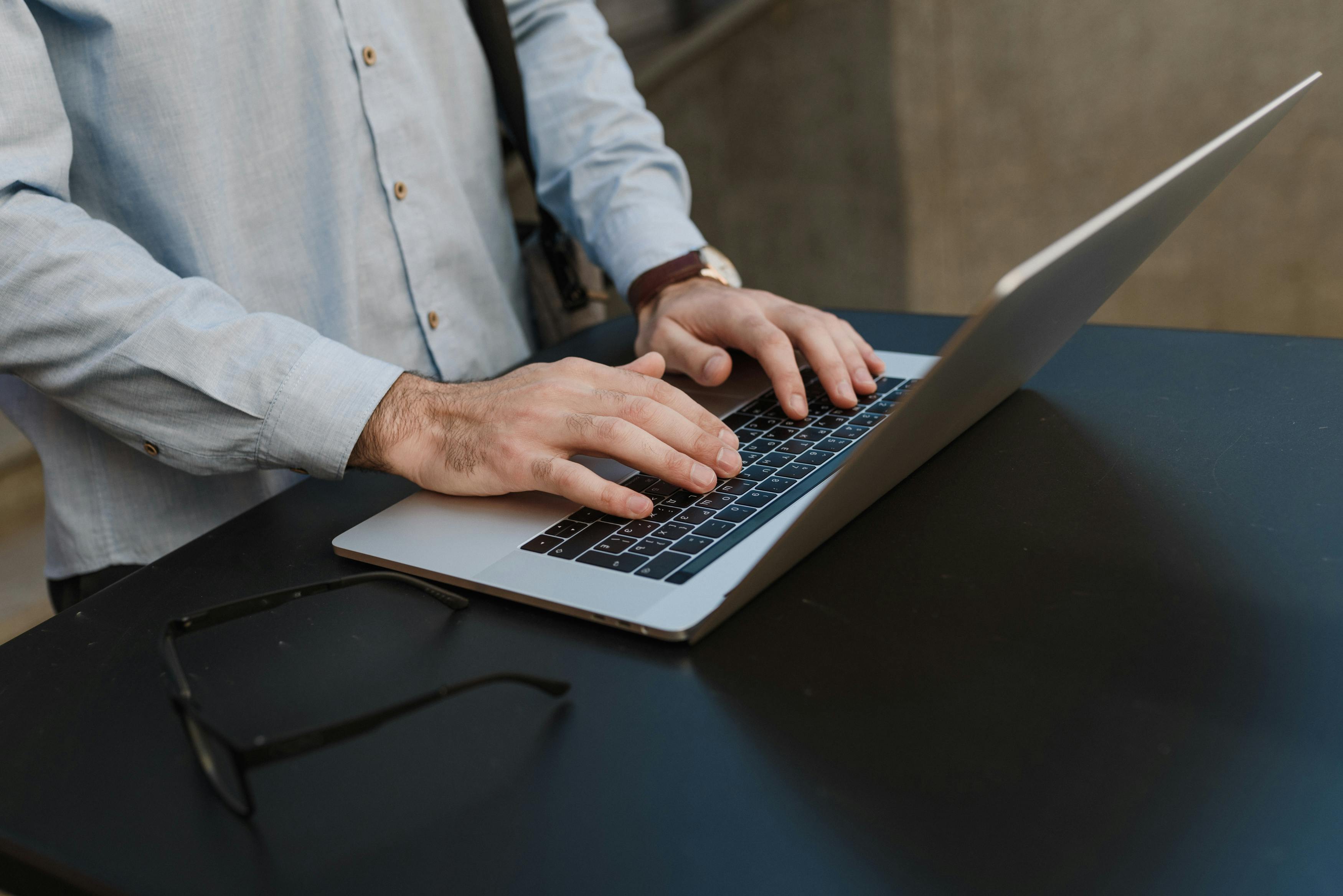Close-up of hands typing on a laptop, suited for business or work imagery.
