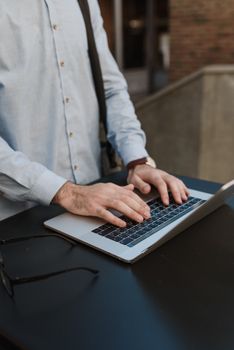 Close-up of a freelancer working on a laptop while standing outdoors, highlighting remote work