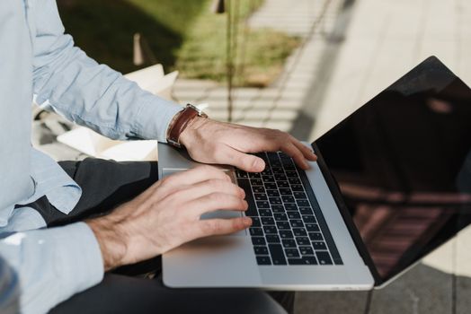 A man working on a laptop outdoors, exemplifying remote and flexible work environments.