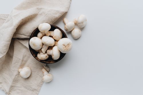 Free Top view of fresh white mushrooms in a bowl on a rustic cloth, perfect for culinary themes. Stock Photo