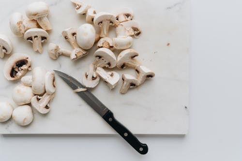 Free Sliced Mushrooms Beside A Knife On White Surface Stock Photo
