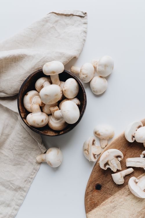 Free Aesthetic top view of fresh white mushrooms in a bowl and cutting board for culinary inspiration. Stock Photo