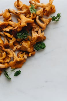A close-up shot of fresh chanterelle mushrooms with parsley on a marble surface.