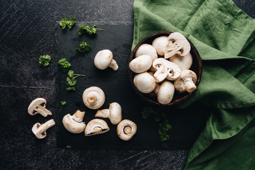 Free Top view of fresh white mushrooms on slate with parsley and green cloth, perfect for food blogs. Stock Photo