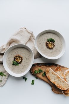 Top view of two bowls of creamy mushroom soup with parsley garnish and toasted bread slices.