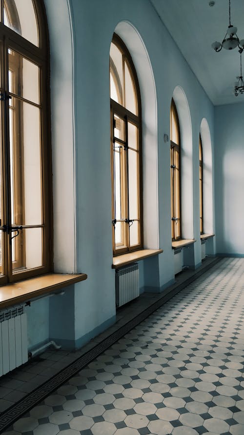 Interior design of spacious light hallway with arched windows and tiled floor in daylight