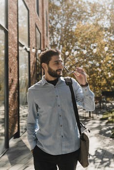 一个穿着时髦休闲装的男人，在办公楼外自信地享受着阳光明媚的一天