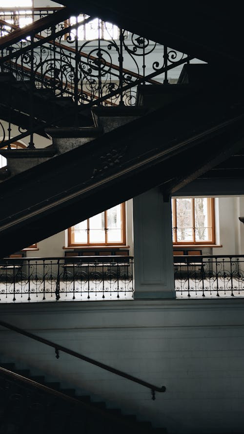 Stairway flights with ornamental railings located in light spacious mansion hall in daylight