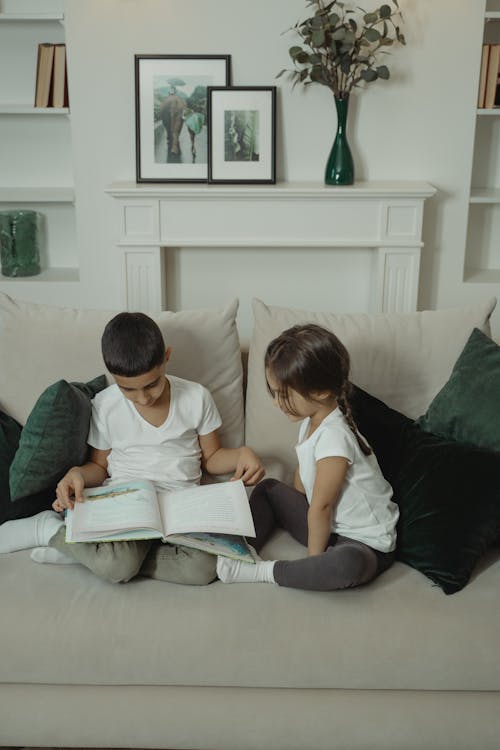 Free Kids Sitting on the Sofa Reading a Book  Stock Photo