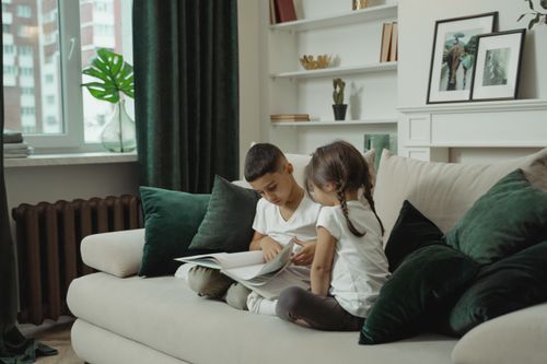 Free A boy and girl reading a book together on a cozy sofa in a modern living room. Stock Photo