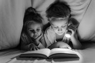 Grayscale Photo of 2 Children Sitting on Bed