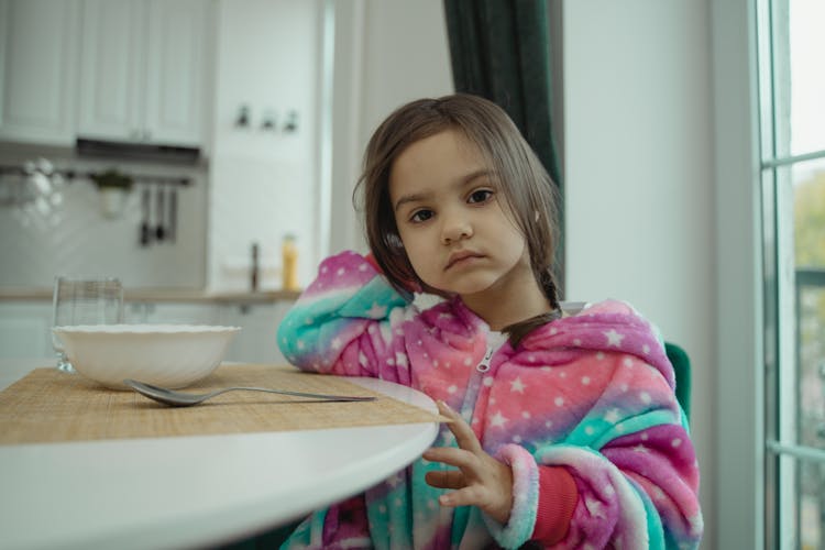 A Young Girl Sitting At The Table