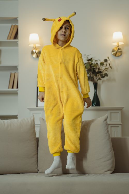 Free Cute child in Pikachu onesie jumping on a sofa indoors Stock Photo