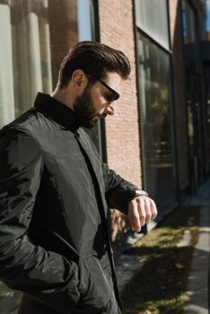 一名男子戴着太阳镜，在户外查看手表的侧面