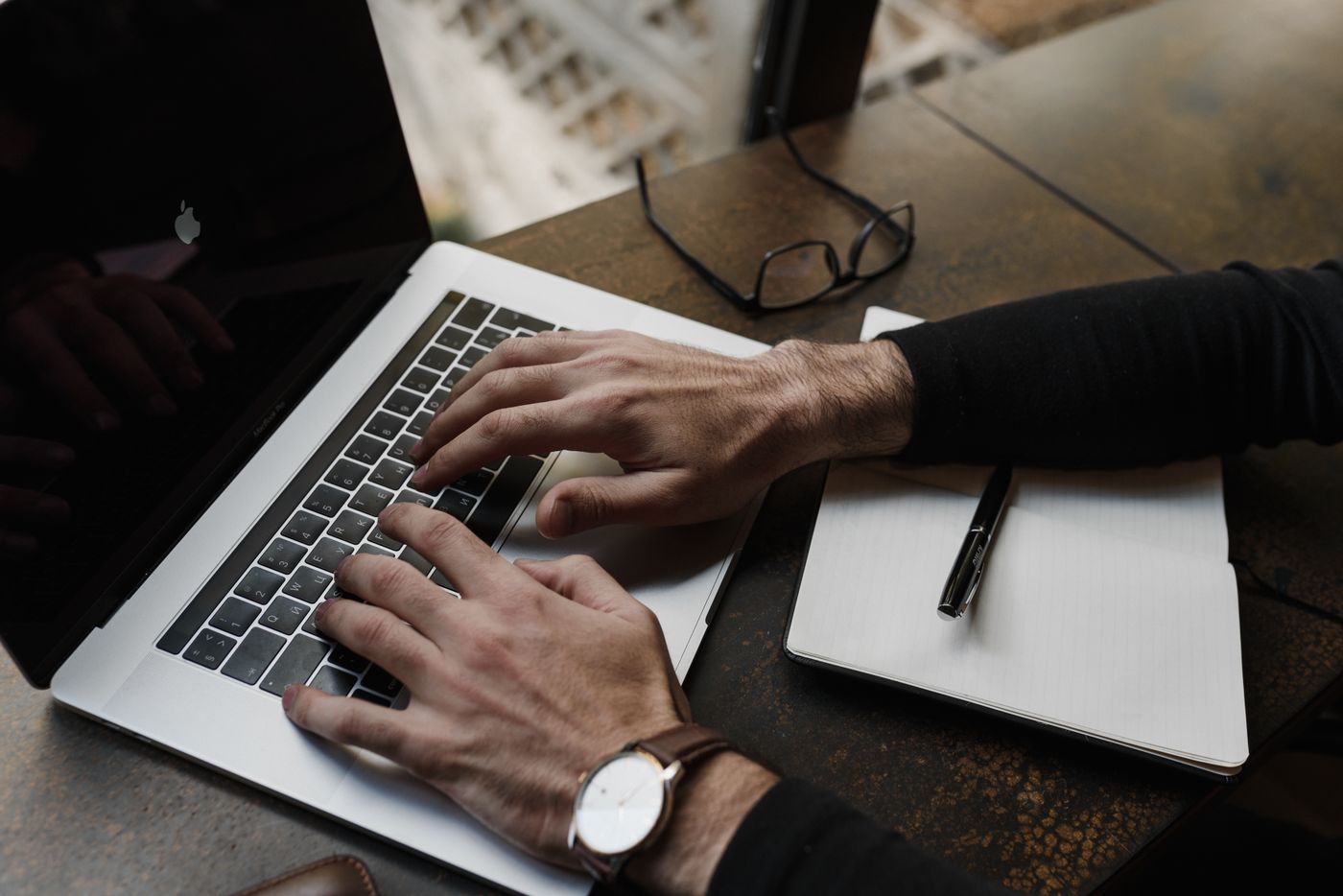 Person typing on a laptop with notes while preparing a WordPress post