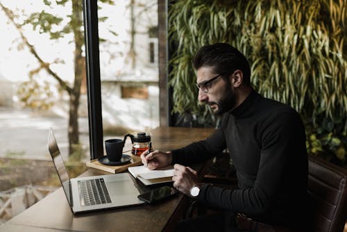 Free A Man using Laptop while Writing  Stock Photo