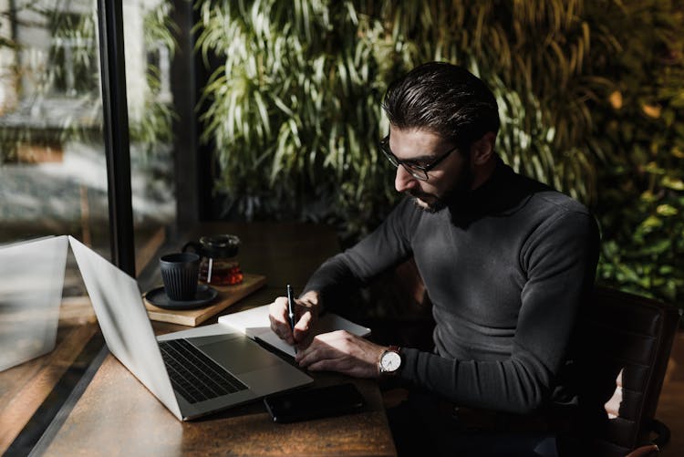 Man In Black Sweater Writing On A Paper