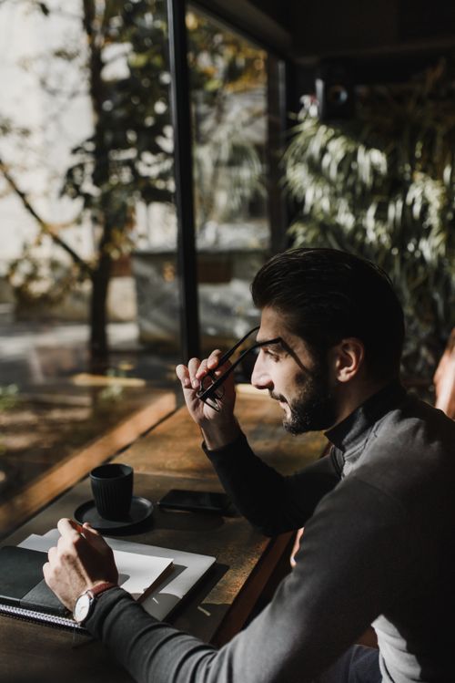 Free Side view of a man working at a desk by a window with natural daylight. Stock Photo