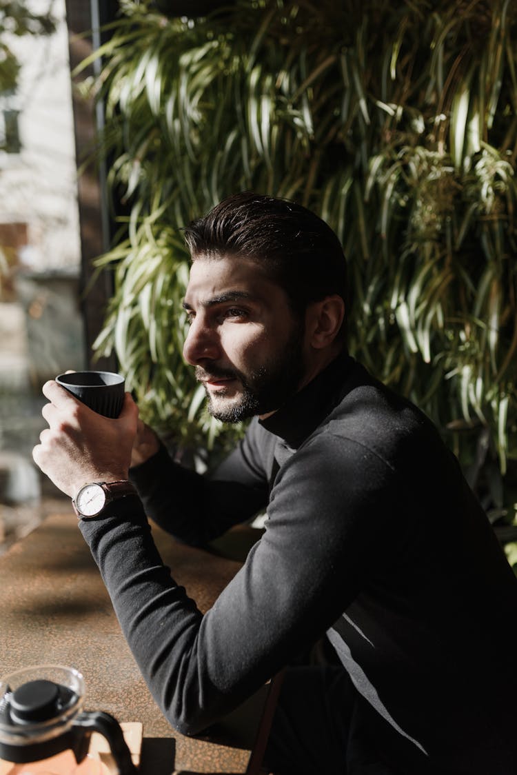 Man Sitting At Desk Holding Black Cup