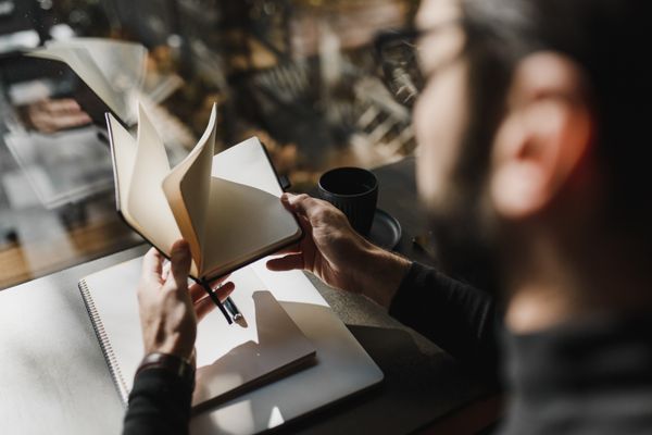 A founder paging back through a notebook beside a laptop — photo by Arina Krasnikova on Pexels