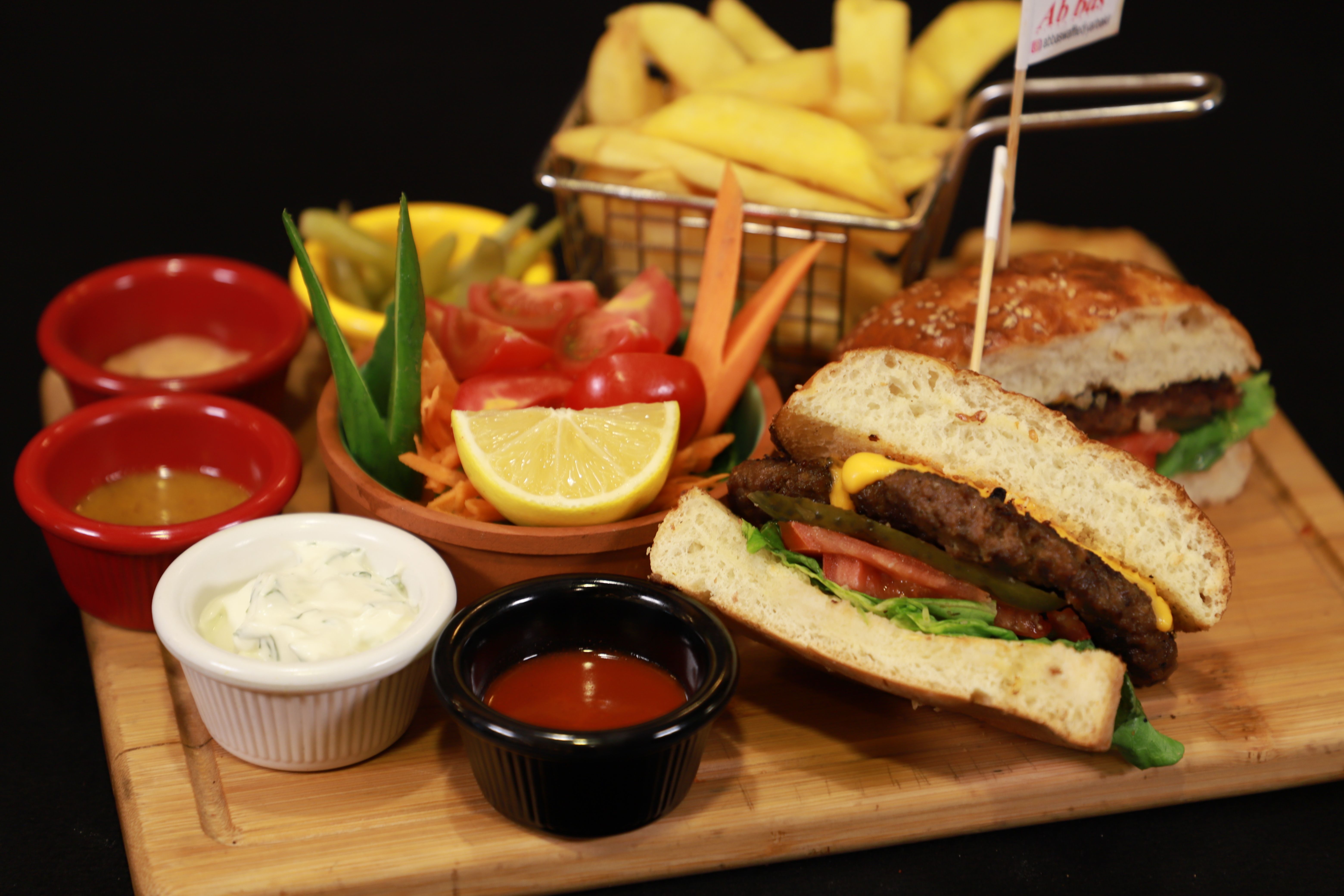 Delicious burger with side of crisp fries and various sauces, perfect for lunch or dinner.