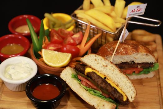 A vibrant food platter featuring a cheeseburger, fries, and assorted sauces. Perfect for fast food lovers.