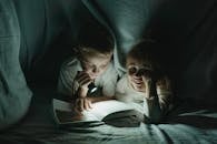 Kids Reading a Book Under the Blanket