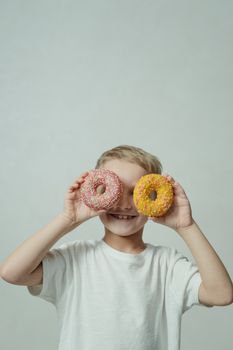 孩子在室内拿着彩色甜甜圈开玩笑