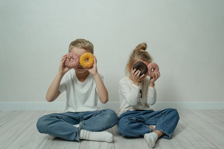 Girl And Boy Fooling Around With Doughnuts