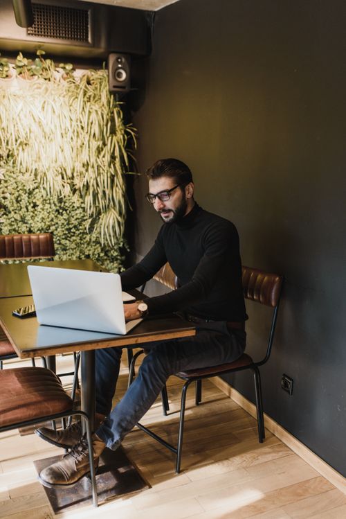 Free Man in glasses typi​ng on laptop at modern indoor workspace. Stock Photo