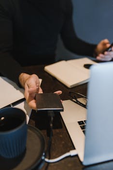 A man at a desk using an external hard drive and laptop, illustrating tech use in a modern office.