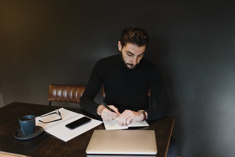 A Person Holding A Pen Looking His Watch