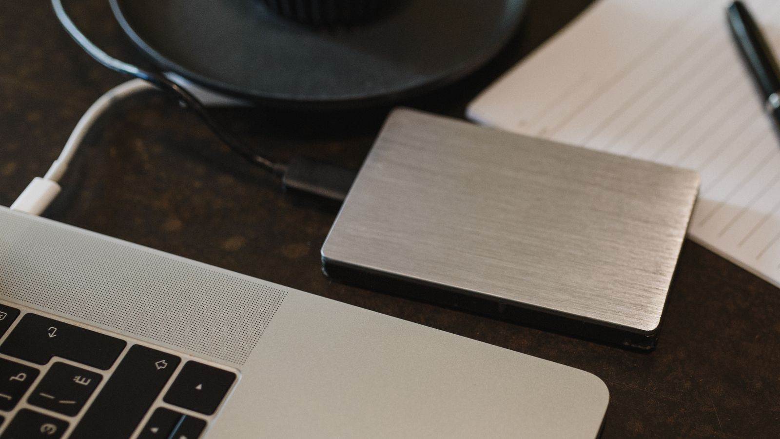 Two external hard drives sitting on a desk next to a laptop