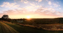 日落时分，乡村的美景展现出田野、树木与宁静的天空