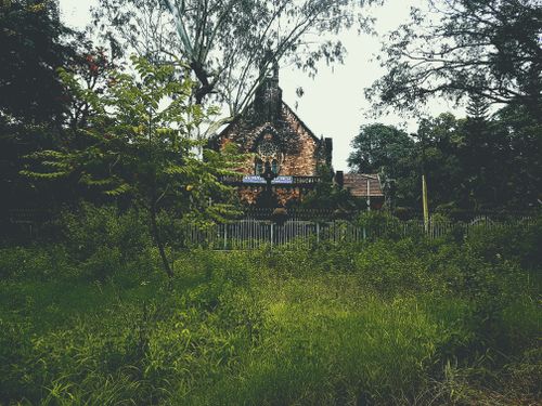 Free A picturesque church set in a lush green countryside with vibrant foliage and clear skies. Stock Photo