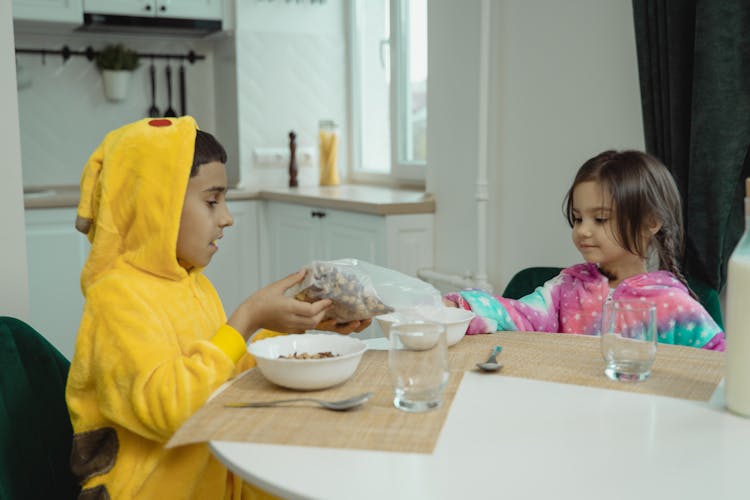 Young Boy Putting Cereal In A Bowl