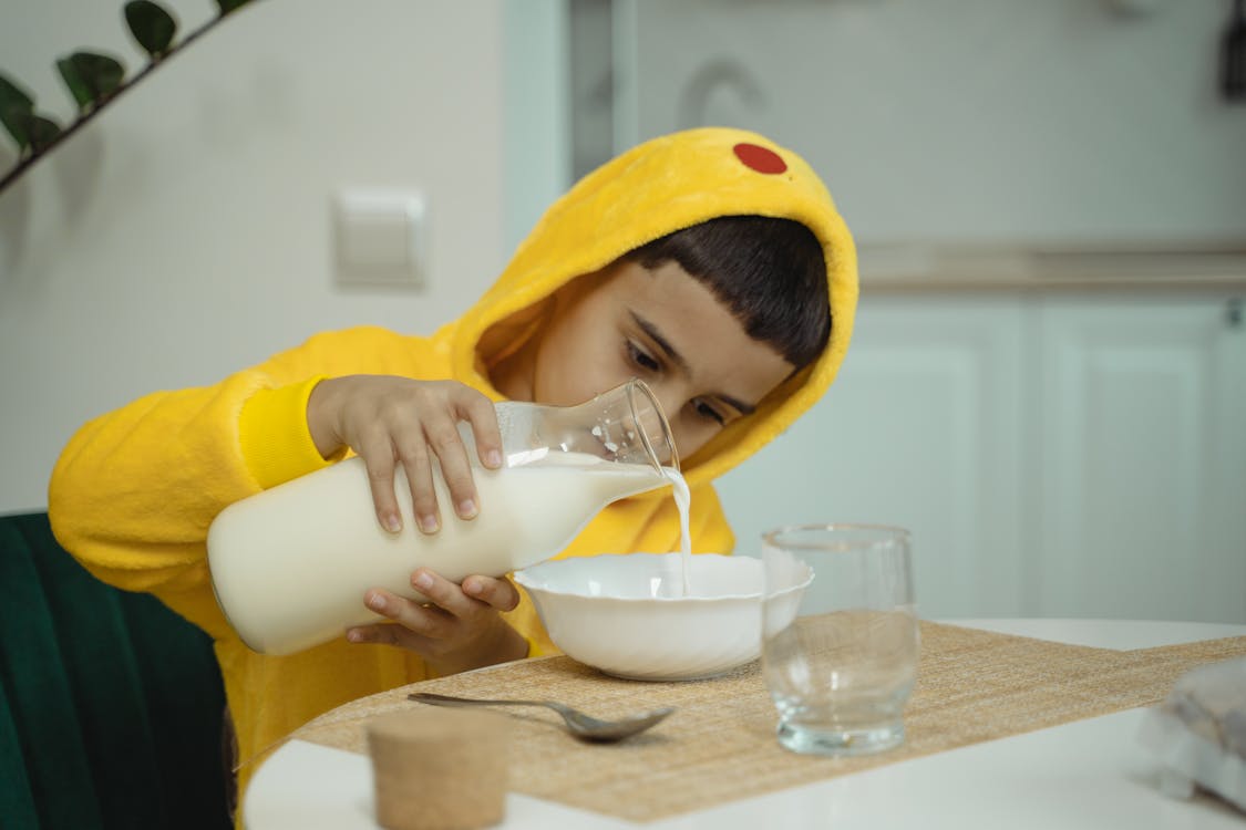Free Boy in Yellow Pajama Holding a Bottle of Milk Stock Photo