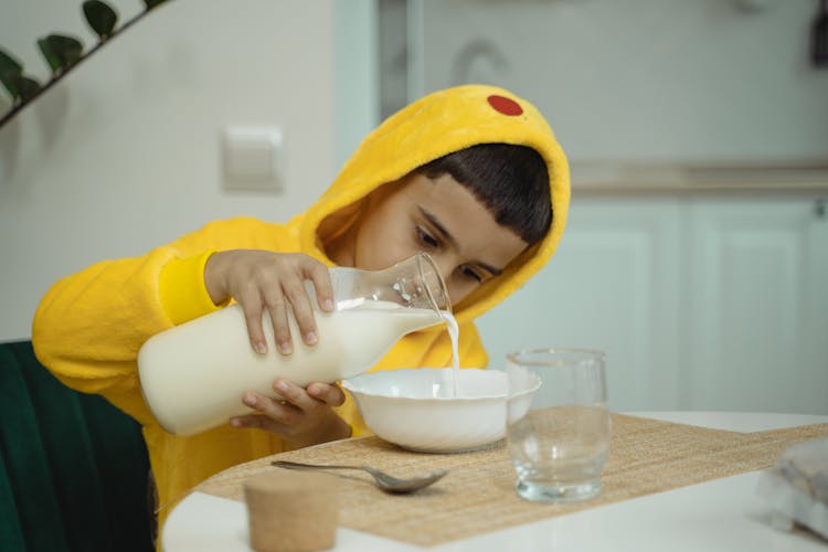 Boy In Yellow Pajama Holding A Bottle Of Milk