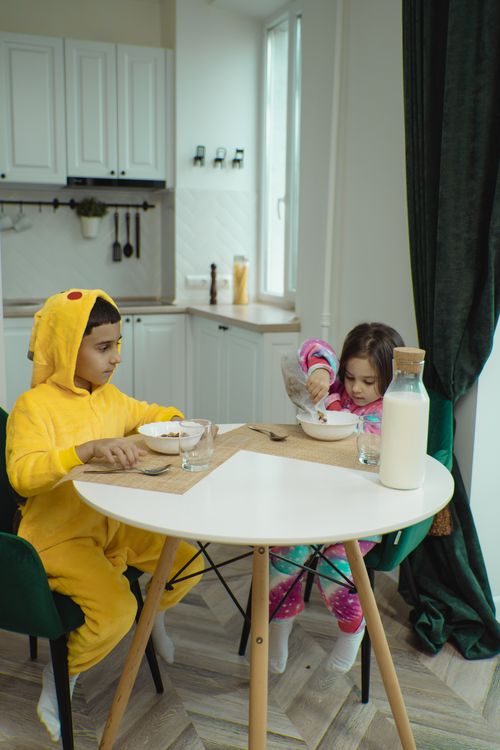 Free Two children in pajamas having breakfast with cereal and milk in a cozy kitchen. Stock Photo
