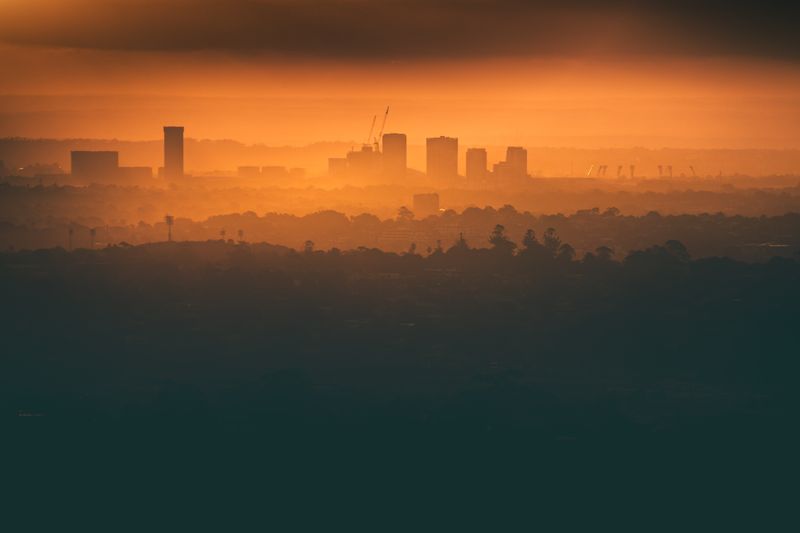 Capturing the Sydney skyline silhouette during a vibrant orange sunset, creating a dramatic urban scene.