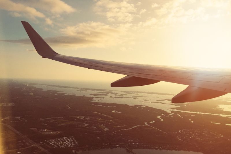 Airplane wing above clouds representing overseas travel